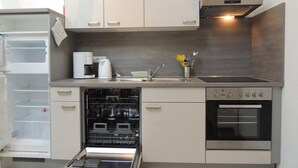 Een moderne keuken met een vaatwasser, oven en koffiezetapparaat.