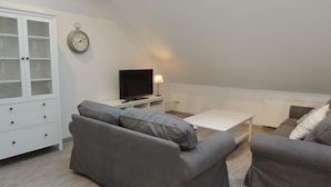 Een loft-woonkamer met een zithoek, een televisie en een kast.