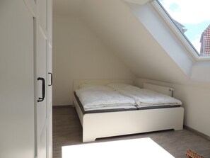 A bedroom with a sloped ceiling, a bed, a radiator, and a skylight. - Apartment Himmel Kirchstraße 3 Whg. 3 - Apartment Himmel (Wittmund)