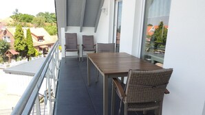 Un balcon avec une table et des chaises, une vue sur le quartier et une balustrade.