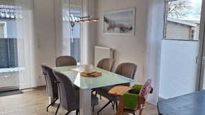 A modern dining area with a glass table, chairs, and a view of the outdoors.