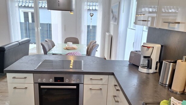 A modern kitchen with a Bosch oven, a coffee maker, and a dining area with a glass table and chairs.