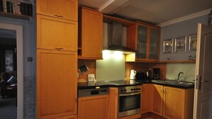 A compact kitchen with wooden cabinets, a stove, and a sink. - Vacation home Mühlenstraße 12 Nr. 1 - Holiday home Mühlenstraße 12 Nr. 1 in (Wittmund)