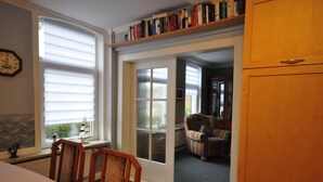 A cozy room with a dining table, chairs, a bookshelf, and a door leading to another room. - Vacation home Mühlenstraße 12 Nr. 1 - Holiday home Mühlenstraße 12 Nr. 1 in (Wittmund)