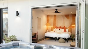 A modern bedroom with a large bed, a ceiling fan, and a hot tub in the foreground. - Ventana Cove Pickleball and Saltwater Pool (Yucca Valley)