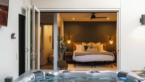 A modern bedroom with a large bed, a hot tub, and a ceiling fan. - Ventana Cove Pickleball and Saltwater Pool (Yucca Valley)