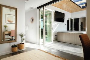 Una cocina moderna con una isla grande, puertas de cristal correderas que dan a un balcón y un televisor de pantalla plana montado sobre la isla.