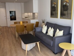 A modern living room with a grey sofa, yellow chairs, a black coffee table, and a small yellow side table.