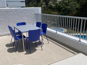 Une terrasse avec une table et des chaises, une piscine et un mur blanc.