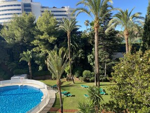 Ein Poolbereich mit einem klaren, blauen Pool, umgeben von Palmen und Grünpflanzen, und ein Gebäude im Hintergrund mit der Aufschrift 'GRAN MERIVA'.