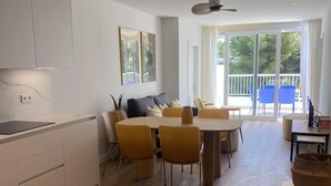 A modern living room with a dining area, large windows, and a view of the outdoors.