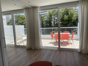 A spacious room with a large sliding glass door leading to an outdoor balcony with a table and chairs.