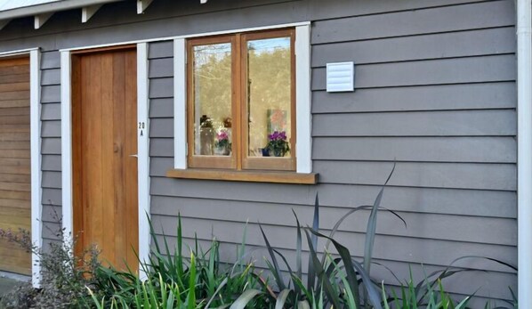 Una casa con revestimiento gris, una puerta principal de madera y un ventanal con marco blanco.