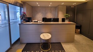 Una moderna recepción con un taburete de mármol, una decoración de árbol de Navidad y vistas al cartel de un hotel.