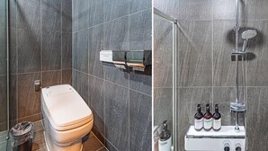 Un baño moderno con inodoro, ducha con cabezal de ducha manual y dispensador de jabón sobre una repisa.