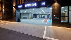 Entrada de un hotel con un cartel que indica 'OUT PARKING IN' y la entrada a un estacionamiento.