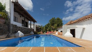 A swimming pool with clear blue water, surrounded by stone walls and a tiled deck.