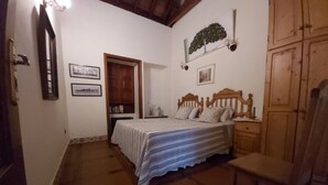 Un dormitorio con una cama, un armario de madera, una silla y una mesita.