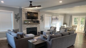 A modern living room with a fireplace, grey sofas, a coffee table, and a TV mounted on the wall. - Modern Cheerful Bluegrass Beauty (Lexington)