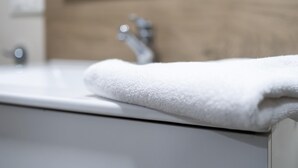 A bathroom with a white sink, a wooden panel above the sink, and a white towel on the edge of the sink. - Housing León Azabachería 2A (León)