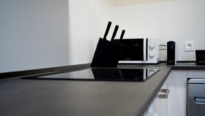 A modern kitchen with a black countertop, a microwave, a coffee maker, and a knife block. - Housing León Azabachería 2A (León)