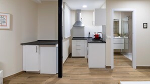 A modern kitchen with white cabinets, a black countertop, and a stainless steel range hood. - Housing León- Azabachería 1B (León)