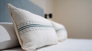 Una cama con ropa blanca y dos almohadas a rayas.
