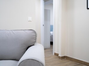 Un salon moderne avec un canapé gris, un plancher en bois et un mur blanc.