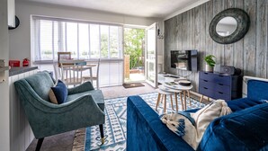 A modern living room with a sofa, a chair, a TV, and a dining area. - No. 33 Apartment 4, Hunstanton, Norfolk (Hunstanton)