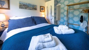 A neatly made bed with blue and white bedding, a bedside lamp, and a wall with patterned wallpaper. - No. 33 Apartment 4, Hunstanton, Norfolk (Hunstanton)