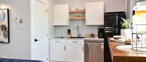 A modern kitchen with white cabinets, a black refrigerator, and a dining area with a wooden table.