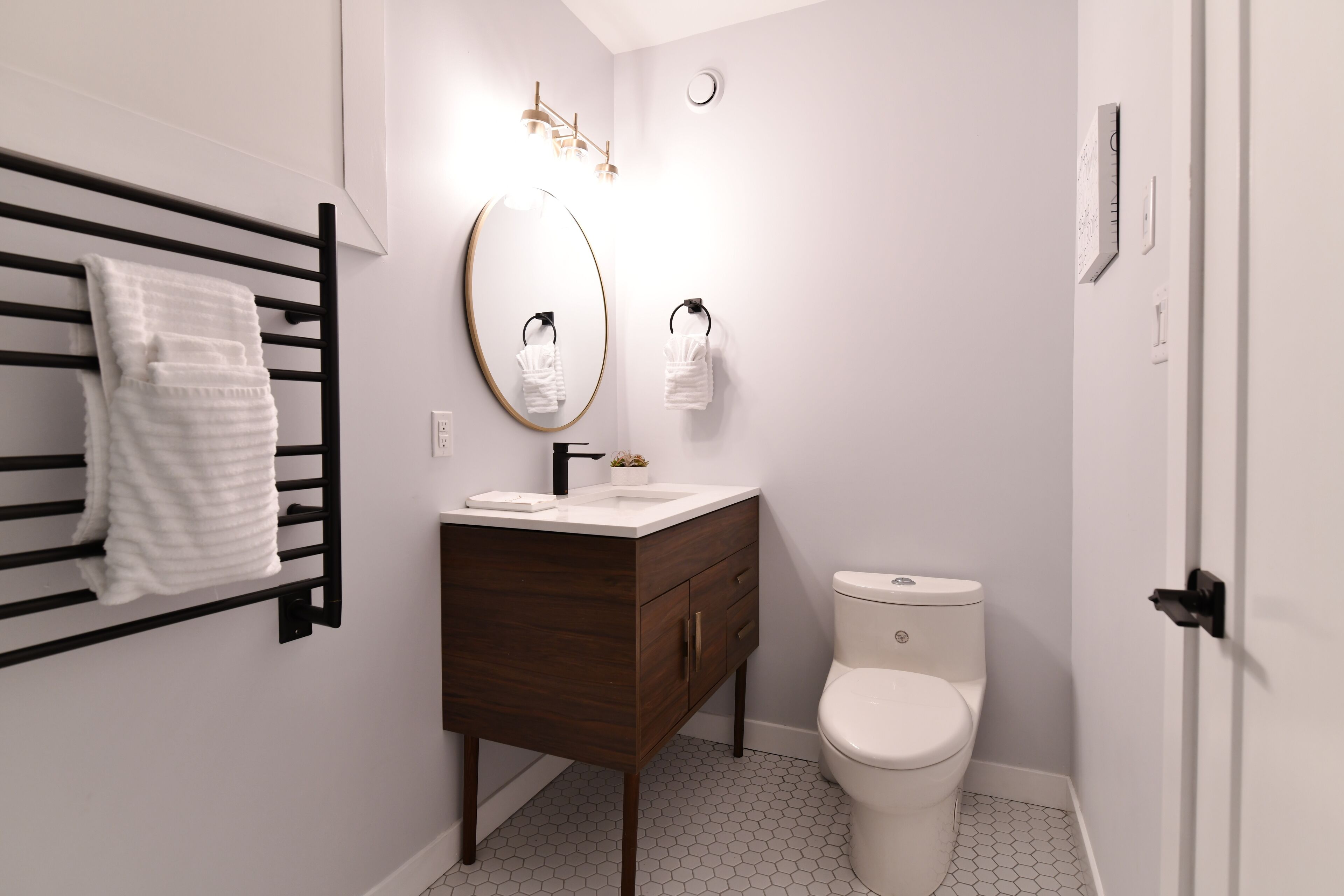 Une salle de bain moderne avec un meuble-lavabo en bois, des toilettes blanches et un porte-serviettes avec des serviettes blanches.