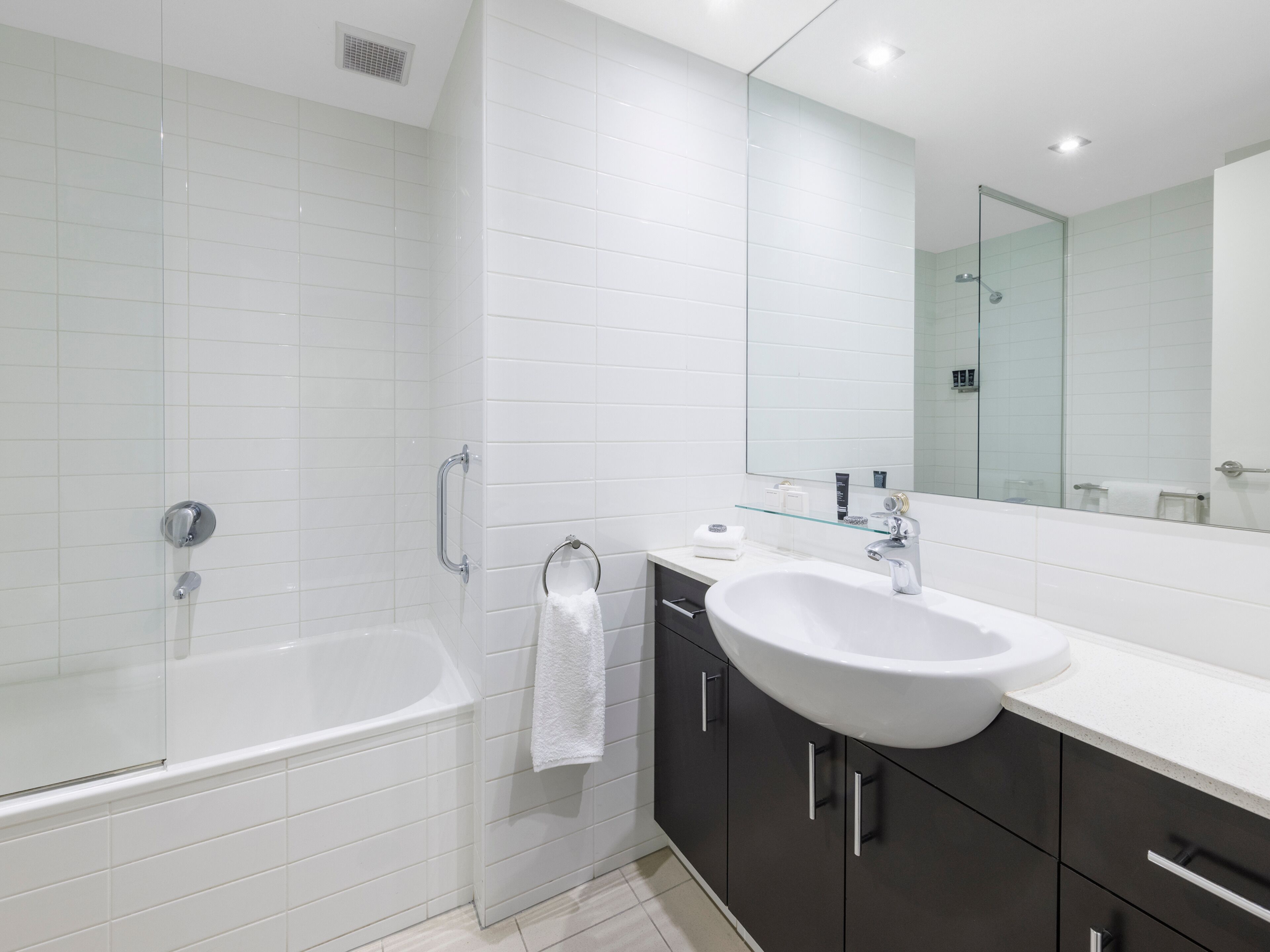 A modern bathroom with a bathtub, a sink, and a large mirror.
