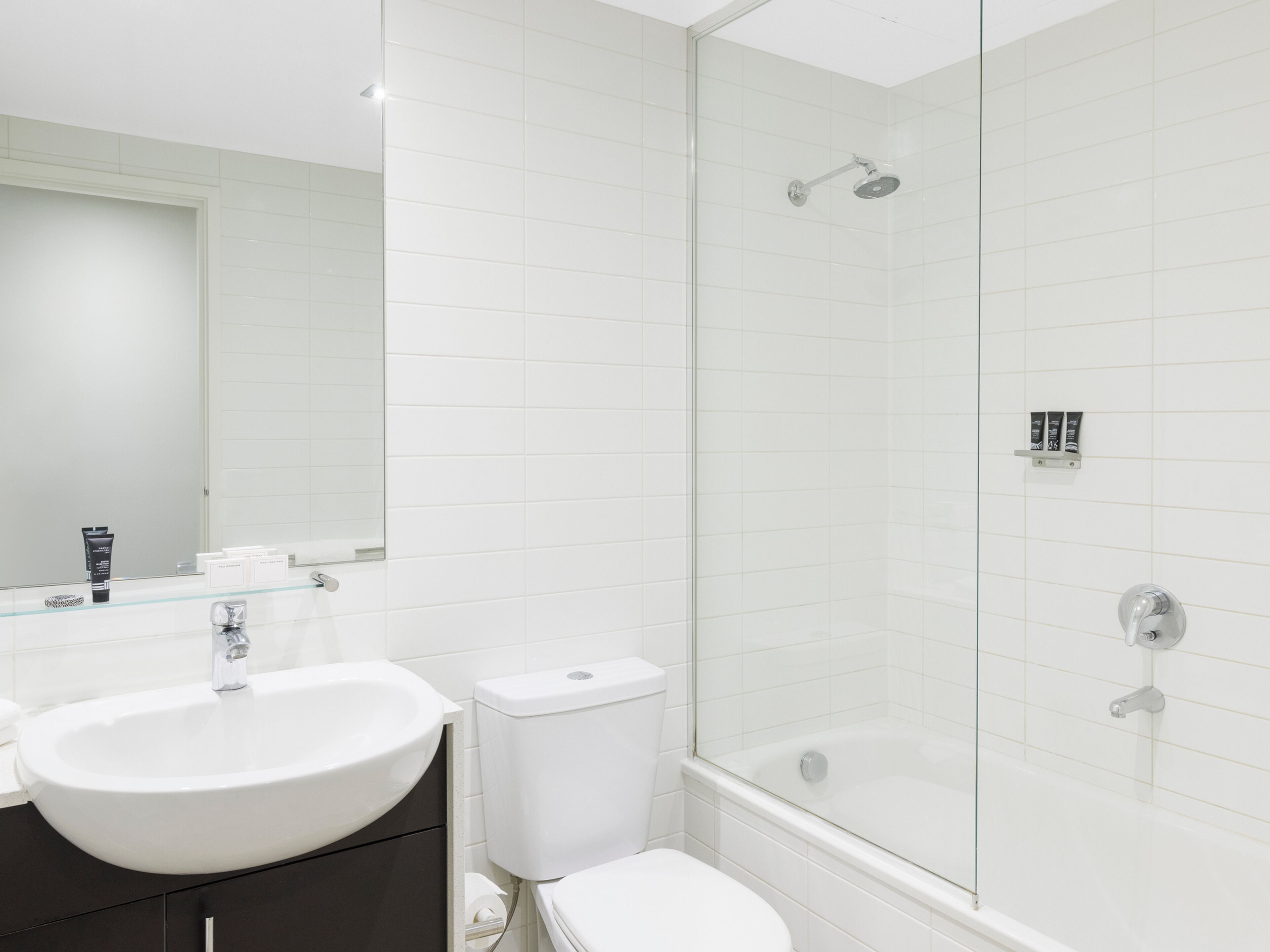 A modern bathroom with a glass-enclosed shower, a white sink, and a toilet.