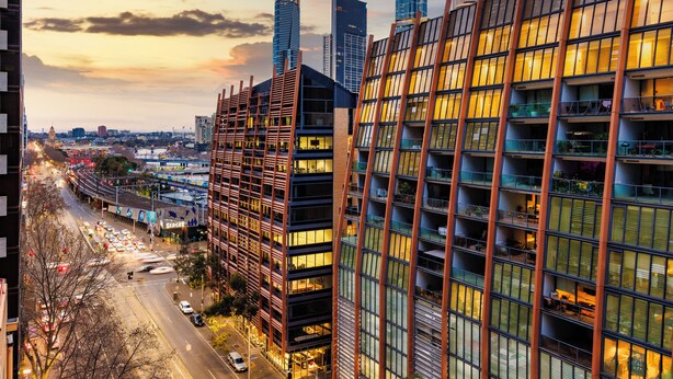 Ein modernes Hochhaus mit mehreren Balkonen und Blick auf eine belebte Skyline im Abenddämmerung.
