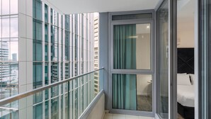 Ein modernes Hotelzimmer mit Balkon, großen Fenstern und Blick auf die Stadt.