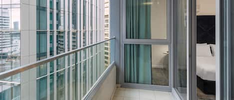 Una habitación de hotel moderna con balcón, ventanas amplias y vistas a la ciudad.