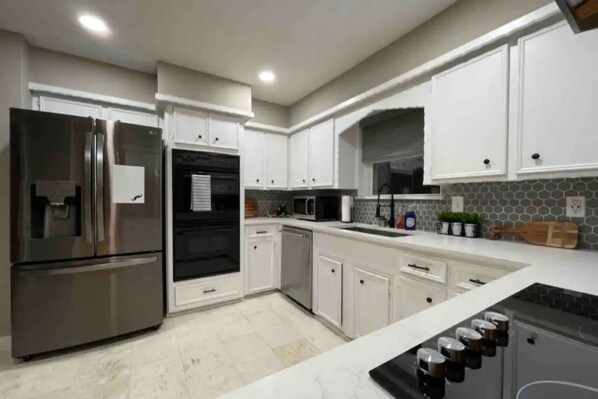 Fully equipped kitchen with stainless steel appliances, white cabinetry, and a range hood.