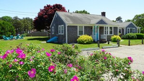A two-story house with a blue slide, a porch, and a well-maintained lawn. - Beach family gateway, modern 5BR, walk to the beach, big yard, firepit (Dennis)