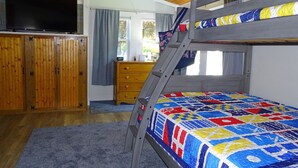 A bunk bed room with a TV, wooden wardrobe, and a desk with a lamp. - Beach family gateway, modern 5BR, walk to the beach, big yard, firepit (Dennis)