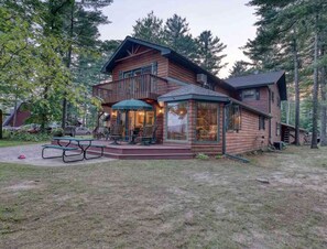A wooden cabin with a deck, a covered patio, and a picnic table.