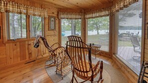Un interior de madera con mecedoras, ventanas amplias y vistas al exterior.