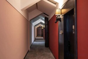 A corridor with a carpeted floor, a red wall on one side, and a black elevator on the other. - Hangzhou Denver Countryside Hotel (Agriculture and Forestry University) (Hangzhou)