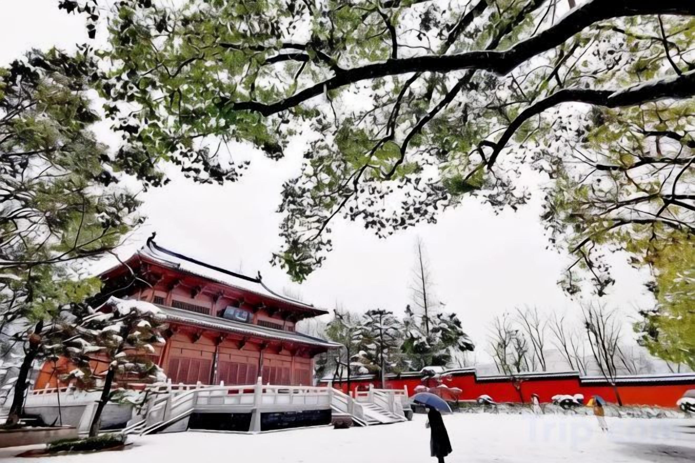 Un bâtiment traditionnel à la façade rouge et au toit blanc, entouré d’arbres et d’un sol recouvert de neige.