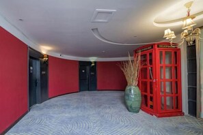 A hotel lobby with a red telephone booth, a large vase with dried plants, and a patterned carpet. - Hangzhou Denver Countryside Hotel (Agriculture and Forestry University) (Hangzhou)