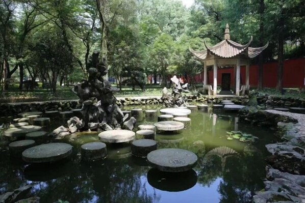 A traditional Chinese pavilion with a pond and stepping stones.