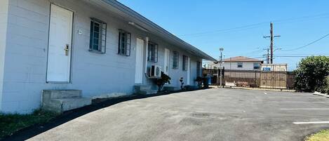 A single-story building with a garage door, a small porch with a bench, and a clear sky.