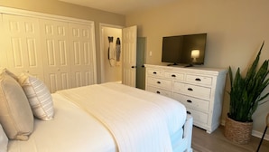 A bedroom with a bed, dresser, television, and a plant. - Renovated 1st Floor 2 Bedroom Condo close to pool and beach with outdoor space. (Ocean City)