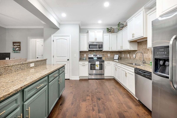 Kitchen with white and green cabinets, granite counters, stainless appliances