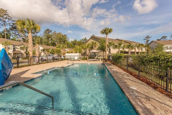 A swimming pool with a clear blue water, surrounded by a fence and palm trees. - Minutes away from restaurants and activities and c (Saint Simons Island)